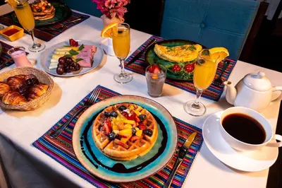 a table with a breakfast of waffles and fruit at Union Hotel Cusco in Cusco