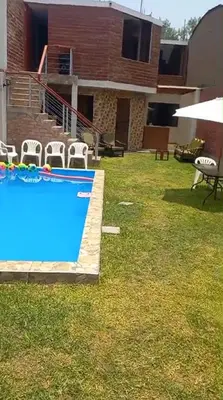 a backyard with a swimming pool and chairs and a house at Casa Halcones Huachipa Familia & Eventos in Lima