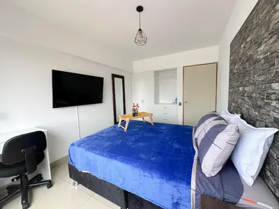 a bedroom with a bed and a chair and a television at Miraflores 1 habitación in Lima