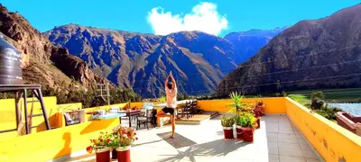 a woman sitting on a balcony with a view of mountains at Mountainview House Ollantaytambo in Ollantaytambo