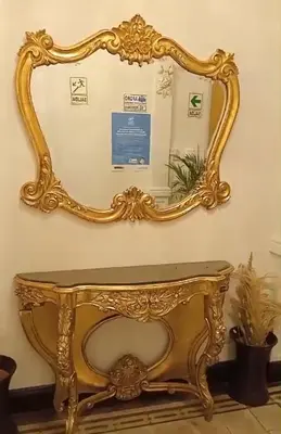 a gold mirror on a wall with a table at Colville Hospedaje, a 1 cuadra de la plaza mayor de lima in Lima