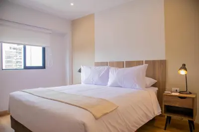a bedroom with a large white bed with a window at Aguirre By Wynwood House in Lima