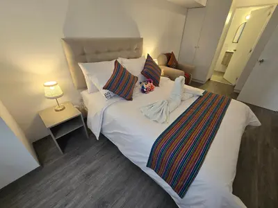 a bedroom with a large white bed with pillows at Acogedor Departamento en Cusco, Ideal para Familias y Amigos, Equipado y Céntrico in Cusco