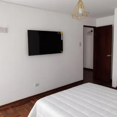 a bedroom with a bed and a flat screen tv on the wall at Bello departamento frente a Larcomar Miraflores in Lima