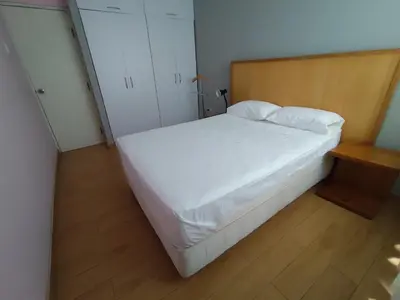 a bedroom with a white bed and a wooden floor at Apartamento Limas Airport in Lima