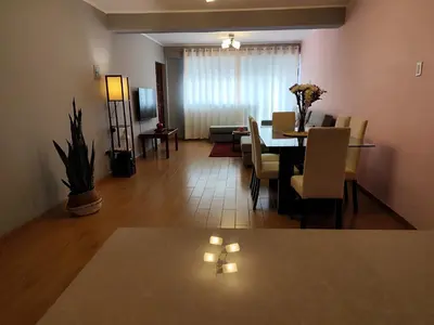 a dining room and living room with a table and chairs at Apartamento Limas Airport in Lima