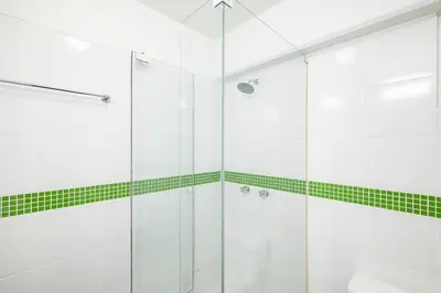 a bathroom with a glass shower with green tiles at M1001 - Malecon Seaview 2BDR Miraflores in Lima