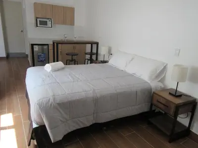 a bedroom with a bed and a table with a lamp at Venue Apartments in Lima