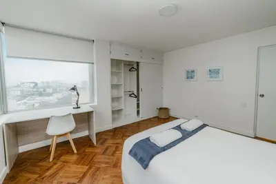 a bedroom with a bed and a desk and a window at Romanet - Depa Premium con Vista al Golf in Lima