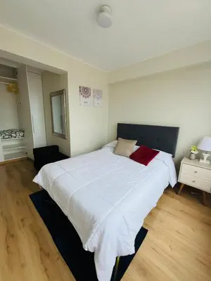 a bedroom with a large white bed with red pillows at Apartamento moderno en San Miguel in Lima