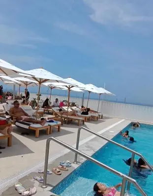 a swimming pool with people in the water and umbrellas at Dpto de Playa Miramar San Bartolo in San Bartolo