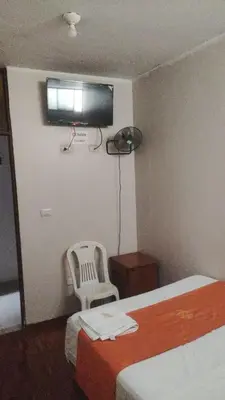 a hotel room with a bed and a chair and a television at hospedaje isla bonita Perú in Huachipa Hacienda