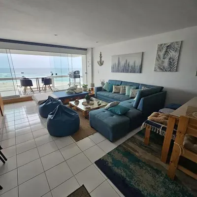a living room with a blue couch and a view of the ocean at Departamento amplio en punta hermosa frente al mar in Punta Hermosa