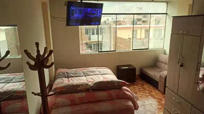 a bedroom with a bed and a couch and a window at Depawanka habitacion amoblado in Huancayo