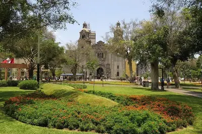 a park with a building in the background with flowers at Apartment in Lima in Lima