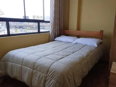 a bed in a bedroom with a large window at Habich Apartment in Lima