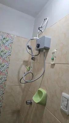a shower in a bathroom with a hose on the wall at Departamento completo acogedor y con estacionamiento in Ayacucho