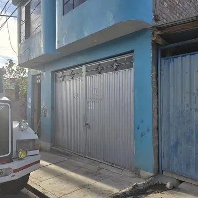 a blue building with a metal garage door on it at Departamento completo acogedor y con estacionamiento in Ayacucho