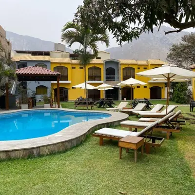 a resort with a pool with benches and umbrellas at Tambo II Hotel Campestre in Cieneguilla