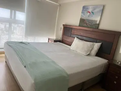 a bedroom with a large bed with a wooden headboard at Urbano Apartments Miraflores Pardo in Lima