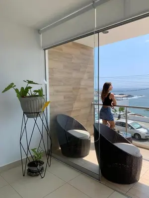 a woman standing on a balcony looking out at the ocean at Departamento San Bartolo, Excellent Location! in San Bartolo