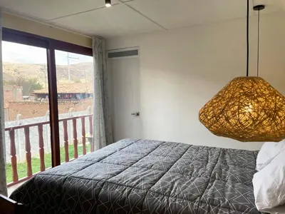 a bedroom with a bed and a large window at La Casa del Valle - Huaripampa in Huaripampa