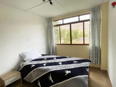 a bedroom with a bed and a window at La Casa del Valle - Huaripampa in Huaripampa
