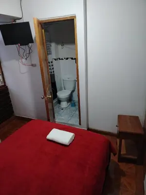 a bedroom with a bed with a red blanket and a mirror at Hospedaje Apu San Isidro in Urubamba