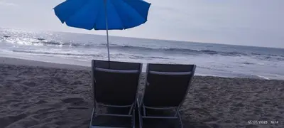 a chair sitting on the beach under an umbrella at Zen Home & Relax - Chincha in Chincha Baja