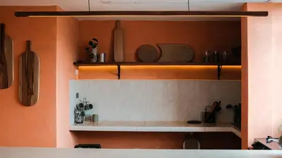 a kitchen with orange walls and shelves with utensils at House Sacha 1BR Great View Huanuco in Huánuco