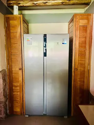 a stainless steel refrigerator in a kitchen with wooden cabinets at Luxury house in Urubamba, Cusco, Perú in Urubamba