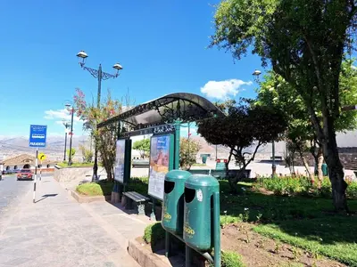 a bus stop with two green trash cans in a park at Jerusalen Inn-Dep 3 in Cusco