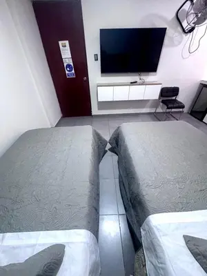 a room with two beds and a flat screen tv at Hotel Gboss in Punta Hermosa