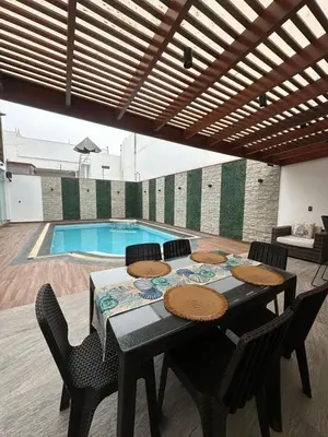a dining room table with chairs and a swimming pool at Casa de Playa en Pulpos Punta Hermosa in Lurín