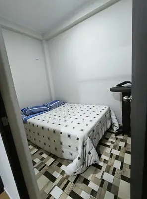 a bedroom with a bed in the corner of a room at Mini departamento acogedor en el centro de Huánuco in Huánuco