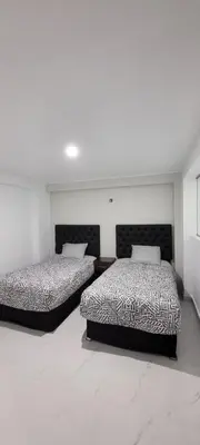 two beds in a room with white walls at La mansión in Cusco