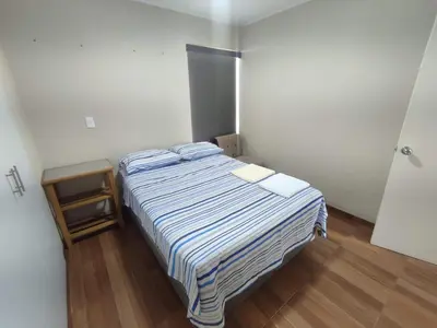 a bedroom with a bed with a striped comforter at Depa moderno - Aeropuerto, San Marcos, Católica in Lima