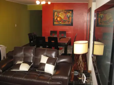 a living room with a leather couch and a table at Cozy Condo in Miraflores in Lima