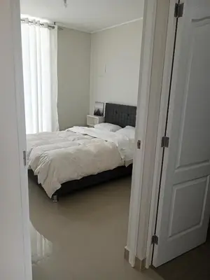 a white bedroom with a bed and a window at Huacachina house in Ica
