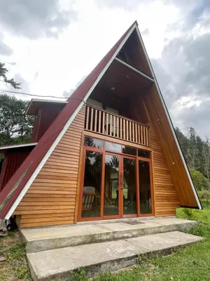 a house with a large roof with glass doors at Cabaña Alpina Yanesh Haus in Oxapampa