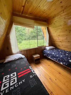 two beds in a room with a window at Cabaña Alpina Yanesh Haus in Oxapampa