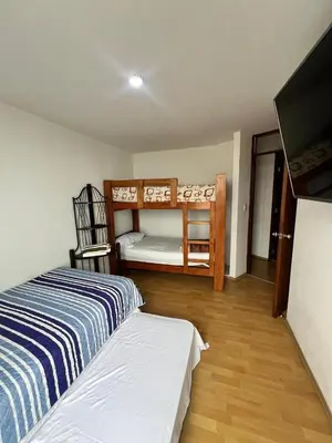 a bedroom with two bunk beds and a flat screen tv at DEPARTAMENTO FRENTE ARENa 1 in Lima
