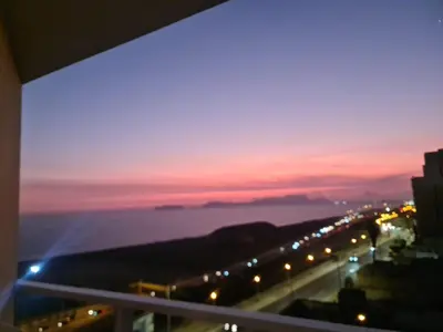 a view from a balcony of a city with a sunset at DEPARTAMENTO FRENTE ARENa 1 in Lima