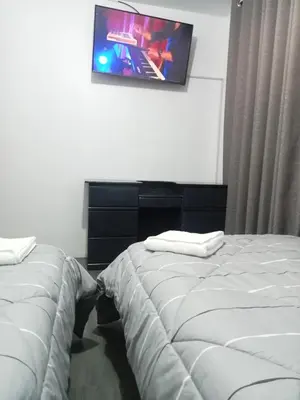 two beds in a hotel room with a tv on the wall at Habitación 02 CAMAS 1C in Lima