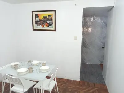 a white table with white chairs and a picture on the wall at Habitación cama QUEEN 1B in Lima