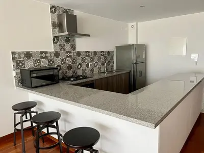 a kitchen with a counter with stools and a refrigerator at Malecón Miraflores Luxury Penthouse in Lima