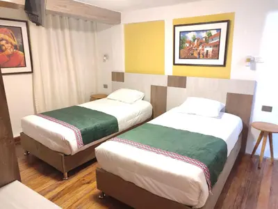 a hotel room with two beds and a table at Patrick's Day Home Cusco in Cusco