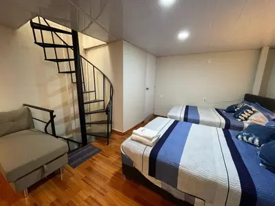 a bedroom with two beds and a spiral staircase at Minidepartamento de 3 pisos, completo y comodo in Cusco