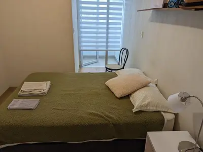 a bedroom with a green bed with a chair and a window at Acogedor y cómodo departamento de 2 Habitaciones en Magdalena in Lima