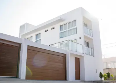 a white house with brown garage doors at CA4 - Casa con Jacuzzi privado - Playa Pulpos in Punta Hermosa
